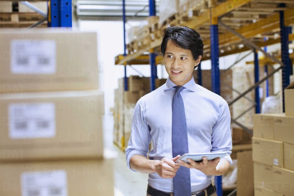 mid adult male manager using digital tablet in distribution warehouse CUF35023